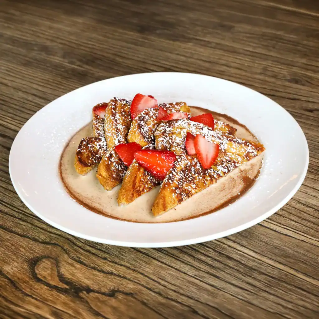 French toast with strawberries and powdered sugar on a white plate.